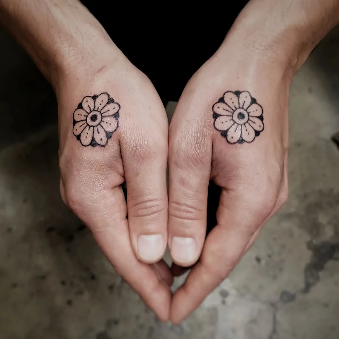 Deux petites fleurs géométriques tradicional en black work sur le dos des mains