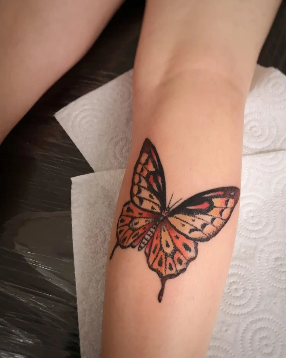 Grand papillon traditionnel en couleur orange et noir sur avant-bras