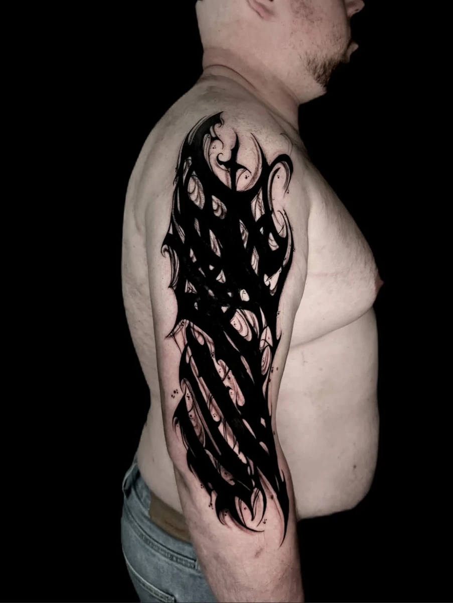 Cover blackwork organique, ancien tattoo absorbé dans le flow du bras.